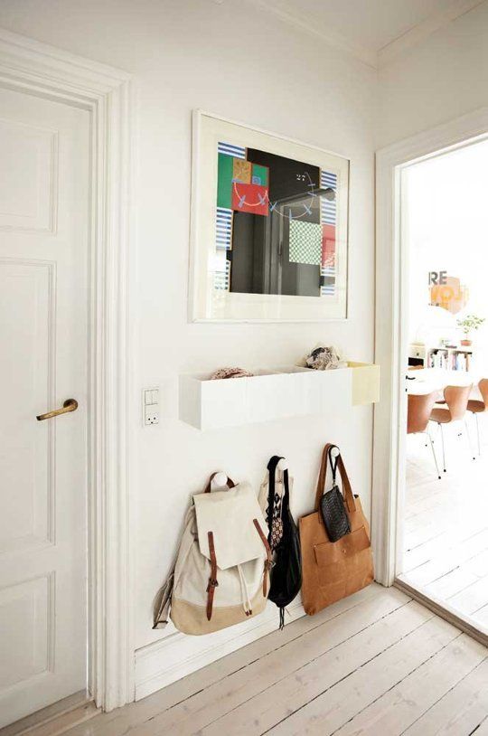 Small white entryway landing strip with wall-mounted storage and hooks
