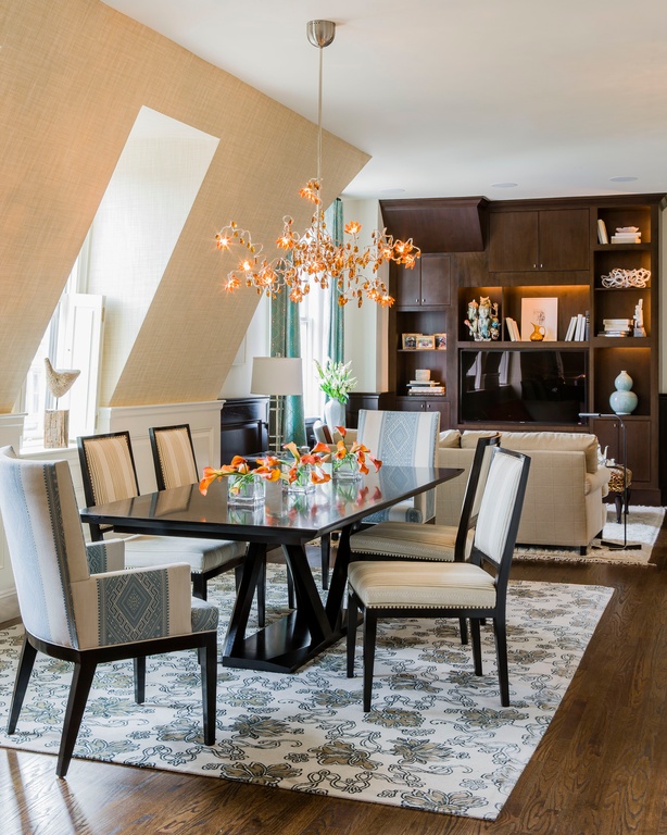 Contemporary dining room with detailed, cushioned dining chairs. A black dining table sits on an area rug