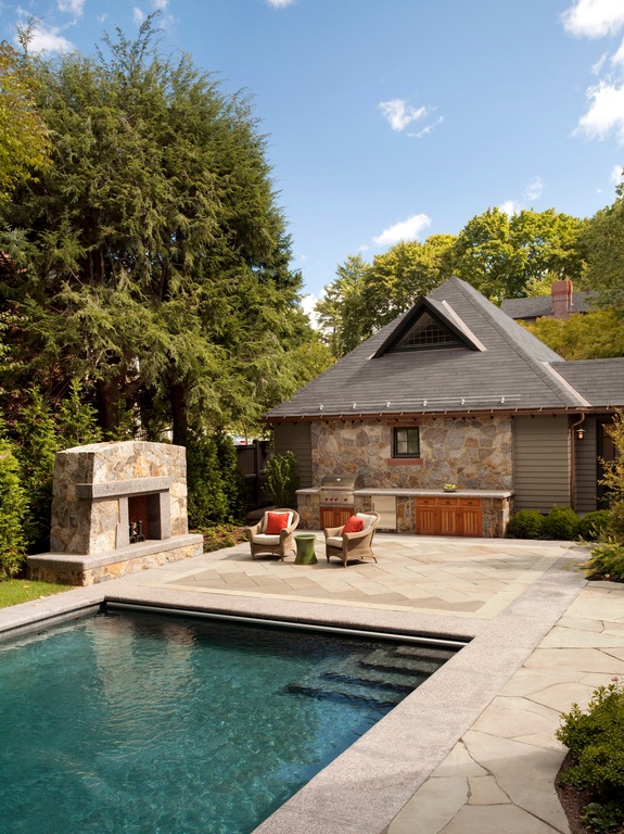 Rustic swimming pool area. Stone fireplace and outdoor, stone kitchen. Patio furniture, including armchairs