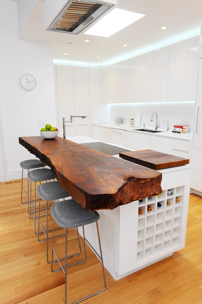 The wood slab kitchen bar counter acts as an artifact within this minimalistic kitchen