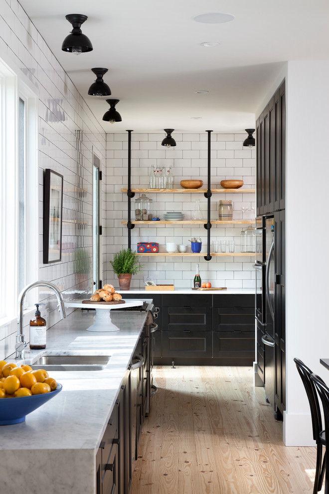 kitchen with black Shaker style cabinets highlighted by Carrera countertops and white subway tiles