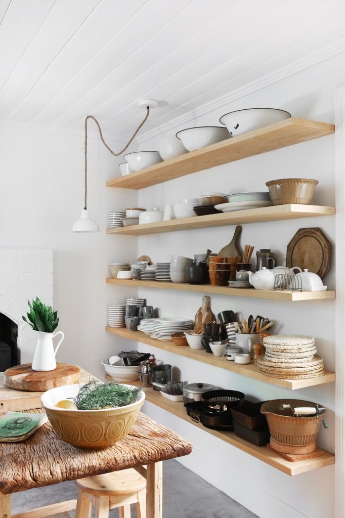 open kitchen storage with vintage crockery, wooden utensils, and chopping blocks