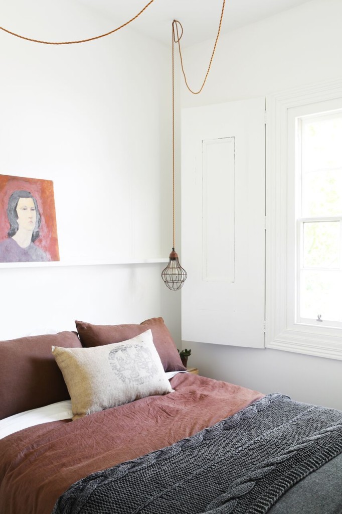 vintage painting propped on a narrow shelf over a Scandinavian interior bedroom