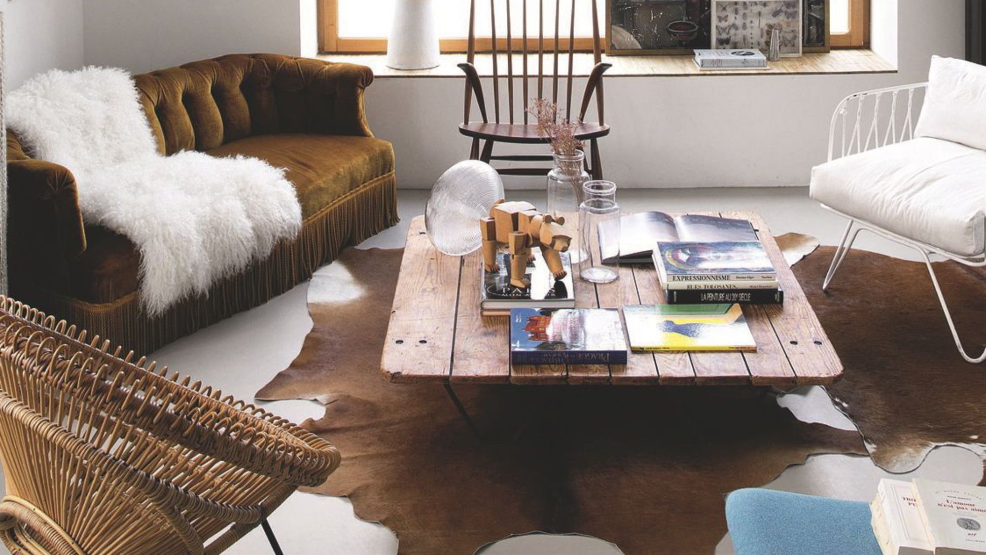 side sitting on cowhide, pallet as a coffee table, rattan chair, velvet sofa, rocking chair