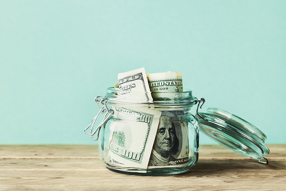 Dollar bills in glass jar. Saving money, economy, finance concept.