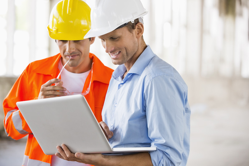 Male architects working on laptop at construction site