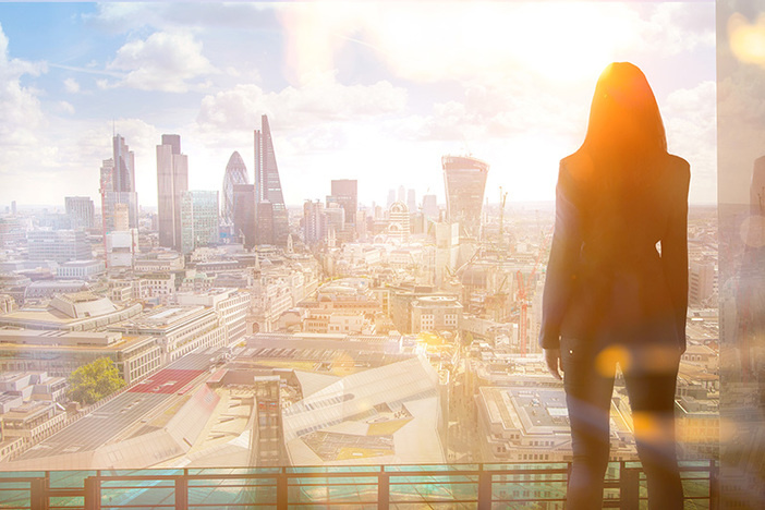Young woman looking over the City of London at sun set. Future,