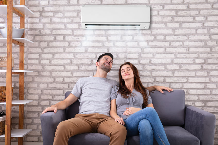 Couple Sitting On Couch Under Air Conditioner
