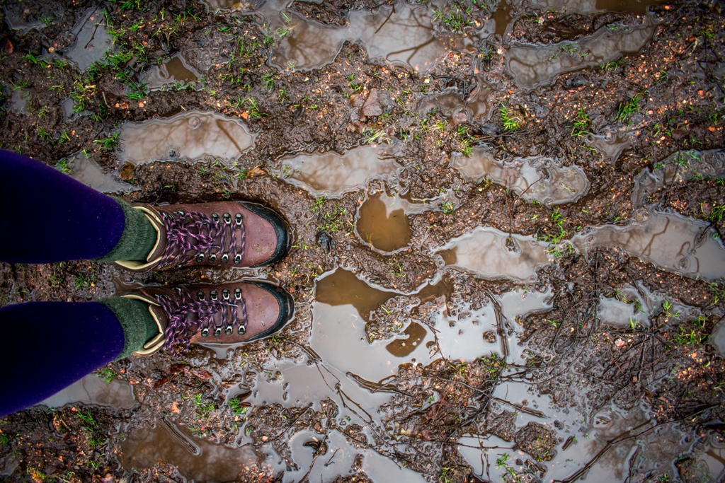 Two feet stading on a muddy, wet path